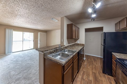A kitchen with a black refrigerator and wooden cabinets.