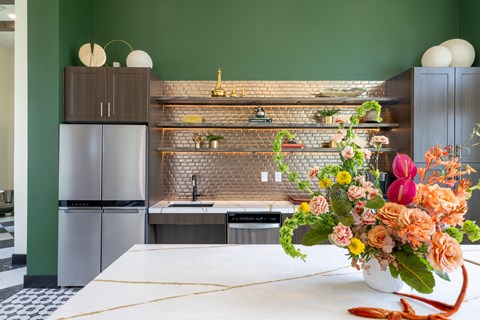 A kitchen with a green wall and a white counter top.