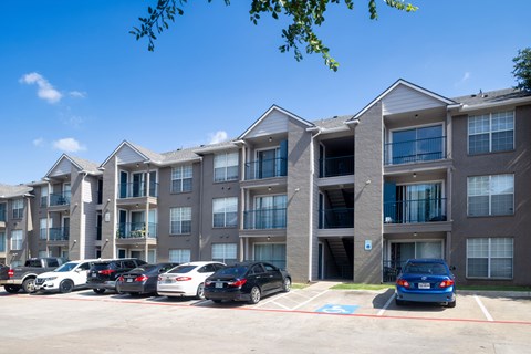 A parking lot with cars and apartment buildings in the background.