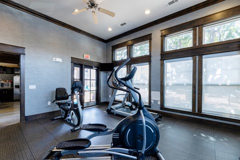 A gym with a row of treadmills and elliptical machines.