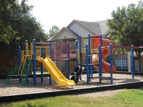 A playground with a yellow slide and a red slide.