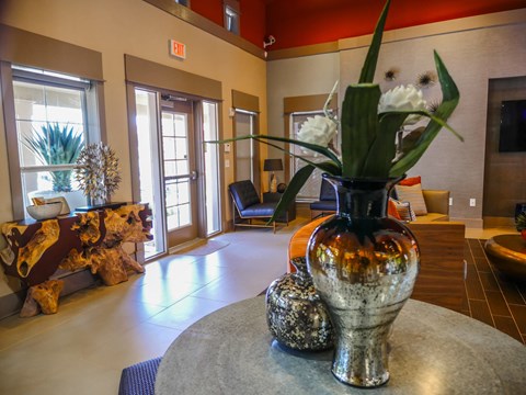A vase with flowers sits on a table in a room with a cow skull on a bench.