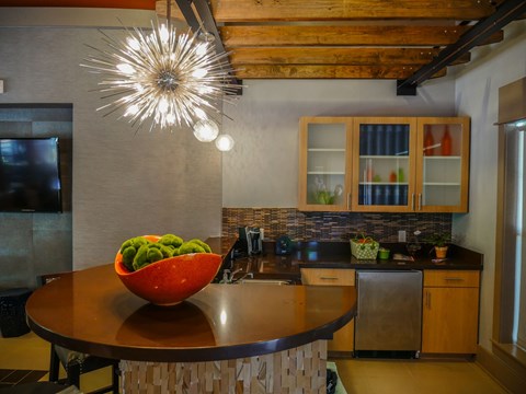 A bowl of fruit sits on a table in a modern kitchen.