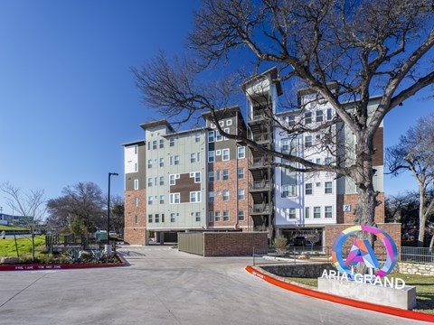 A tall apartment building with a sign that says "ARIA GRAND" in front of it.