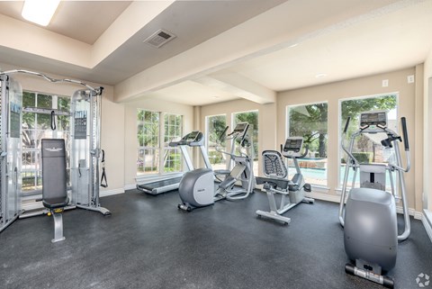 A spacious gym with a variety of equipment including treadmills, elliptical machines, and a weight machine.