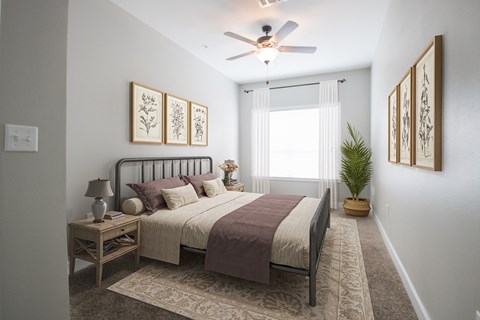 A bedroom with a bed, nightstand, and a ceiling fan.