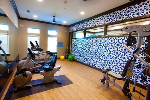 A gym with a row of treadmills and exercise bikes.