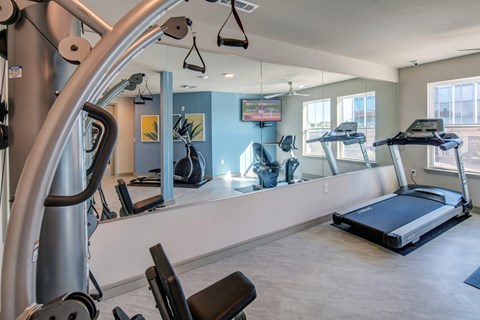A gym with a treadmill, elliptical machines, and other exercise equipment.