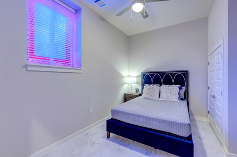 A bedroom with a bed, pillows, and a ceiling fan.