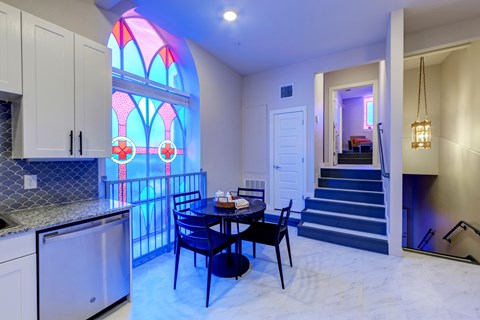 A kitchen with a table and chairs and a stained glass window.