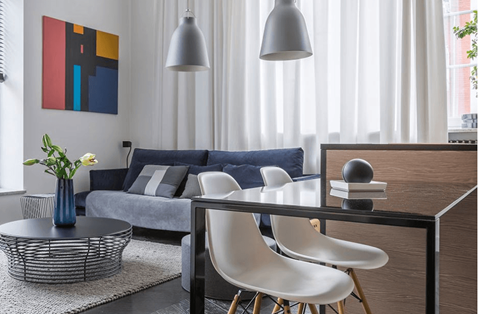 A modern living room with a grey sofa, a coffee table, and a painting on the wall.