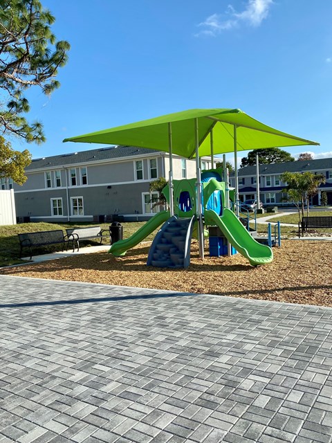 A playground with a green slide and a green canopy.