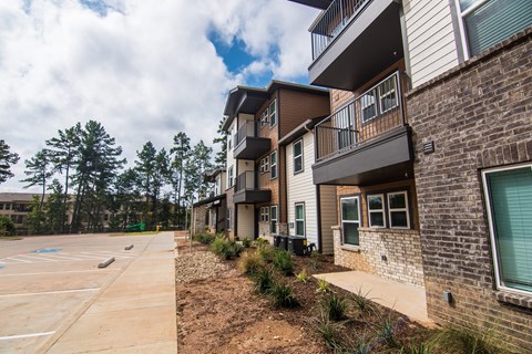 A parking lot is in front of a building with a row of townhouses on the right.