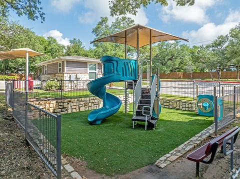 A playground with a blue slide and a yellow umbrella.
