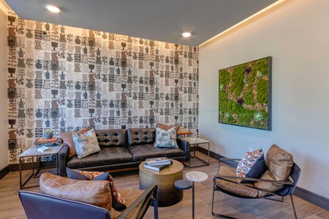 A living room with a couch, chairs, and a painting on the wall.
