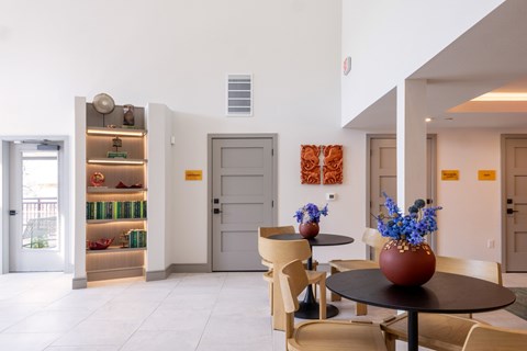 A dining area with a table and chairs and a vase of flowers.
