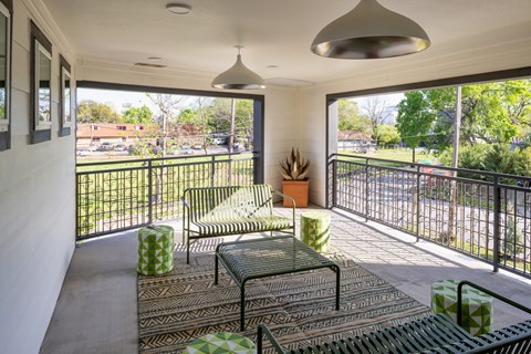 A balcony with a table and chairs overlooking a street.