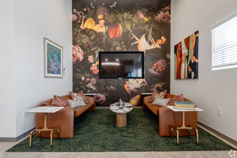 A living room with a large floral wallpaper and a brown leather couch.