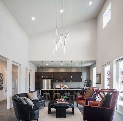A modern living room with a black leather couch and a chandelier.