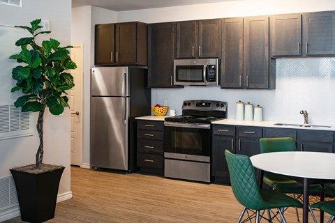 A kitchen with a stainless steel refrigerator, a microwave above the stove, and a dining table with chairs.