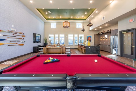 A pool table is in the middle of a room with a red carpet.