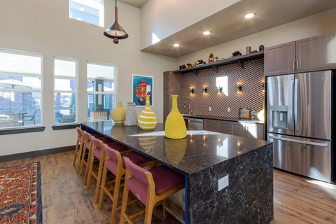 A kitchen with a black counter top and wooden chairs.