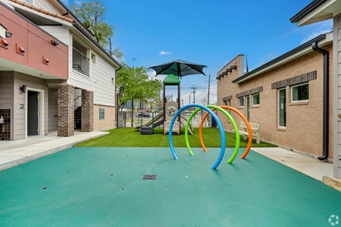 A playground with a green surface and colorful rings.