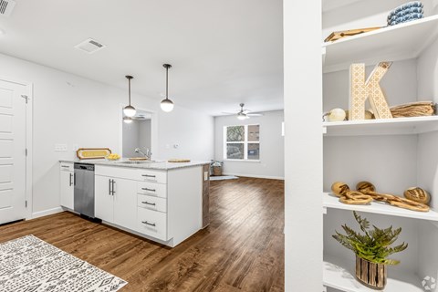 A kitchen with white cabinets and a wooden floor.