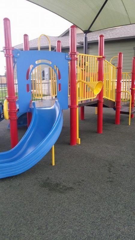 A playground with a blue slide and red and yellow poles.