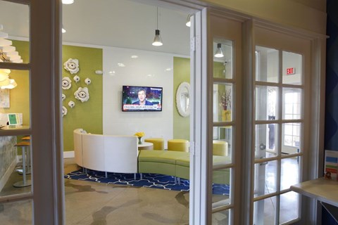 A white couch is in front of a green wall with a TV on it.
