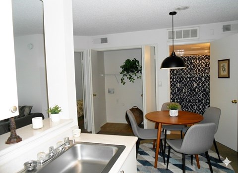 A kitchen with a sink, a mirror, a table and chairs.