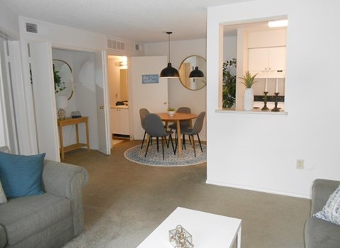 A living room with a grey couch, a white coffee table, and a dining table with chairs.