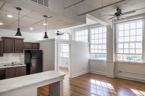 A kitchen with a refrigerator, cabinets, and a marble countertop.