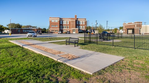 A park with a bench and a pathway leading to a building.