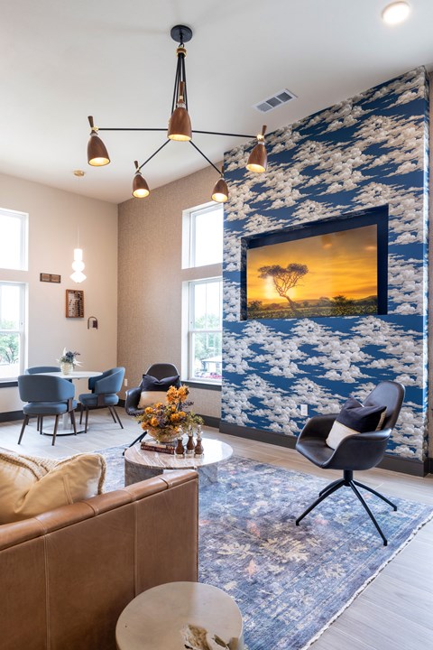 A living room with a large painting of a sunset on the wall.