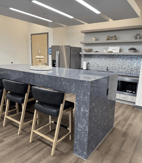 A kitchen with a marble countertop and bar stools.