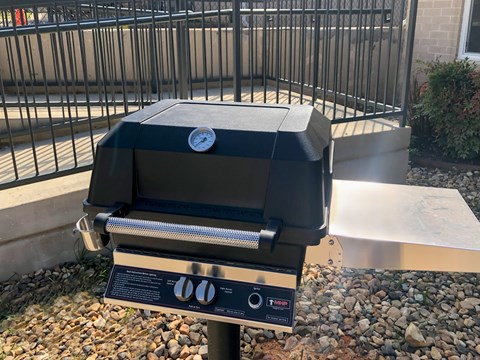 A charcoal grill is placed on a gravel surface.
