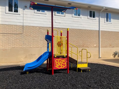 A playground with a blue slide and a red and yellow structure.