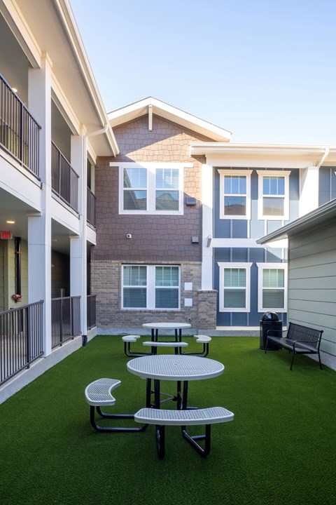 A patio with a table and chairs is surrounded by apartment buildings.