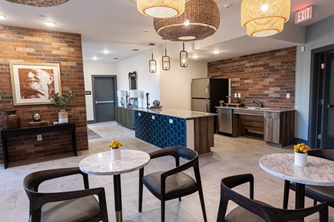 A modern kitchen with a brick wall and a dining table with chairs.