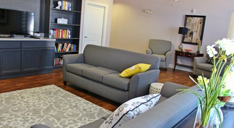 A grey couch with a yellow pillow sits in a living room.