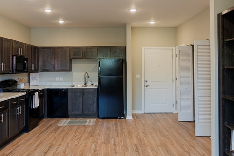 A kitchen with black appliances and wooden floors.