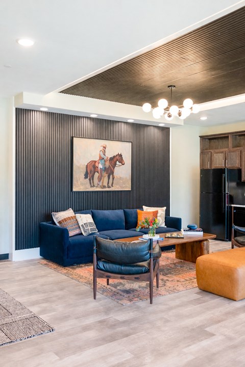 A living room with a blue couch and a painting of a person on a horse.