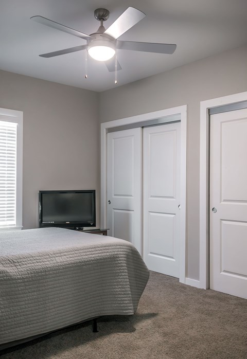 A bedroom with a bed, television, and two doors.