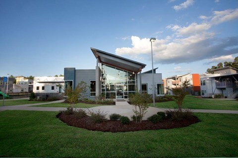 A modern building with a glass entrance and a landscaped front yard.