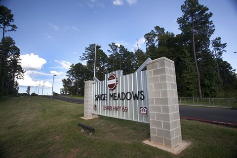 Spice Meadows sign in front of trees and a road.