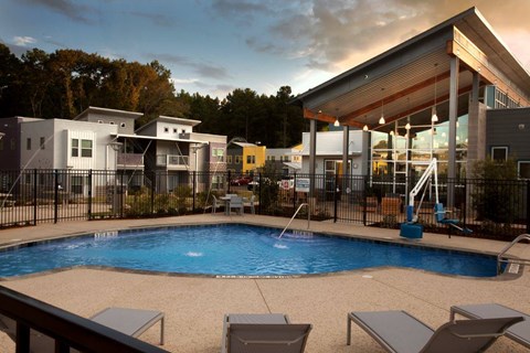 A swimming pool surrounded by lounge chairs and a building in the background.