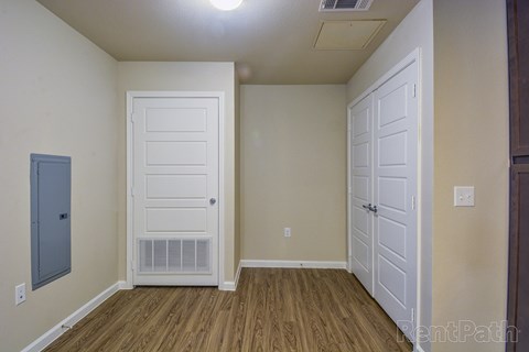 A room with a white door and a brown floor.