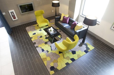 A yellow chair sits on a yellow and black tiled floor in a modern living room.