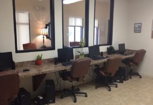 A room with a long table and chairs with laptops on it.
